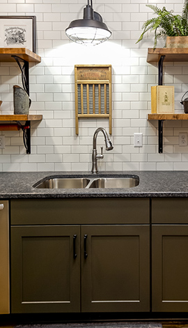 Semi-custom cabinet base in a kitchen setting. There are dark grey countertops and dark cabinets with black hardware on the cabinets.