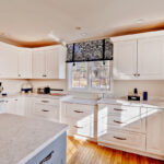 White kitchen cabinets with gray island