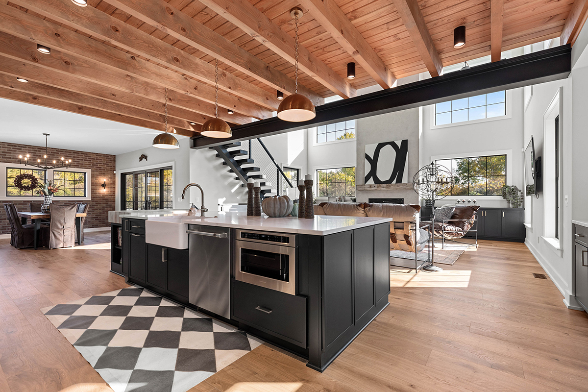 open floorplan kitchen and living room with black cabinetry and beamed wooden ceiling.