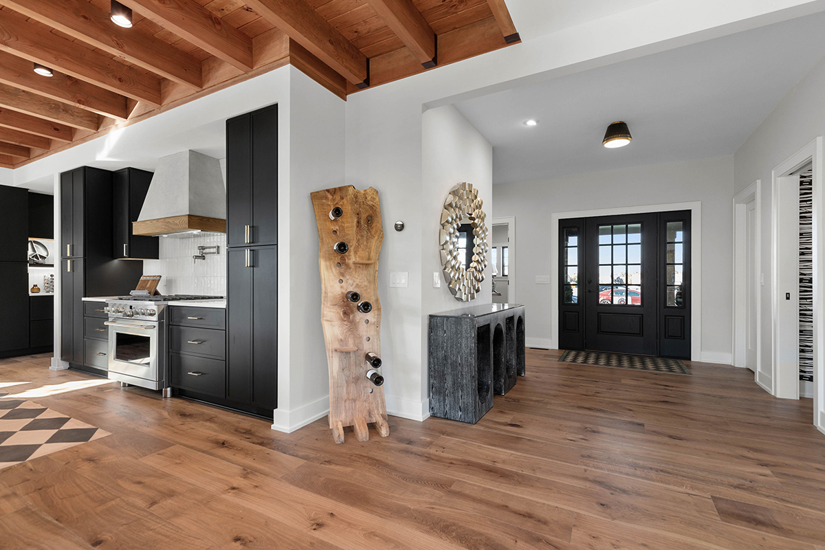 open floorplan leading into kitchen, black cabinetry and brown hardwood flooring