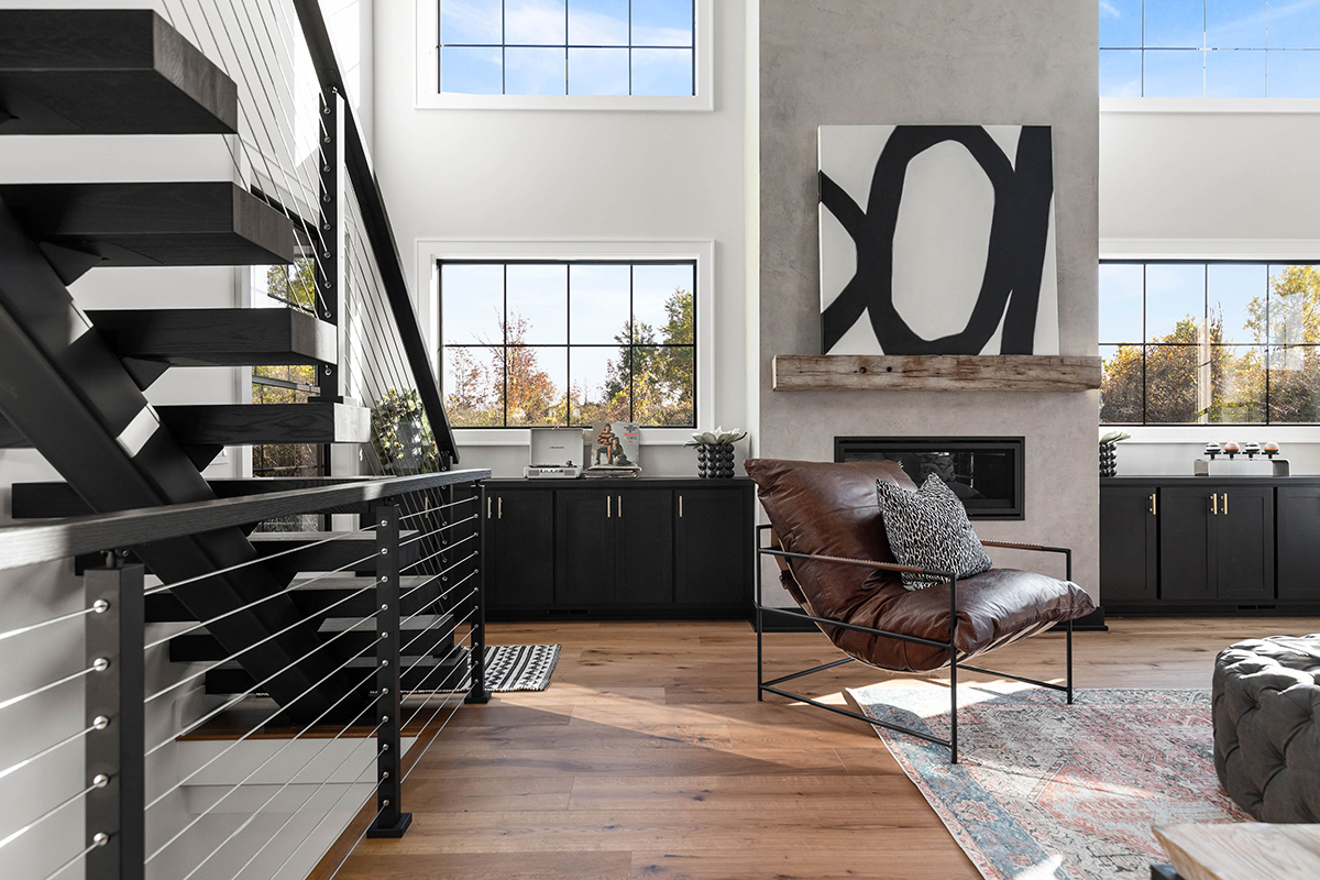 modern living space with black cabinetry and brown hardwood floorplan. Modern wooden black stairs enter into the living room.