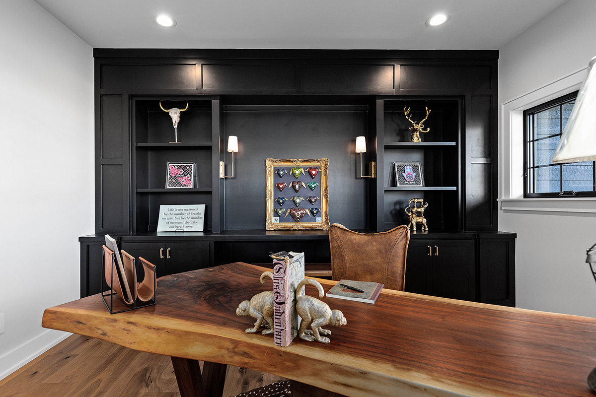 black built-in cabinets in a rustic office. the desk is a live edge piece of wood and the floor is matching wood to the desk.