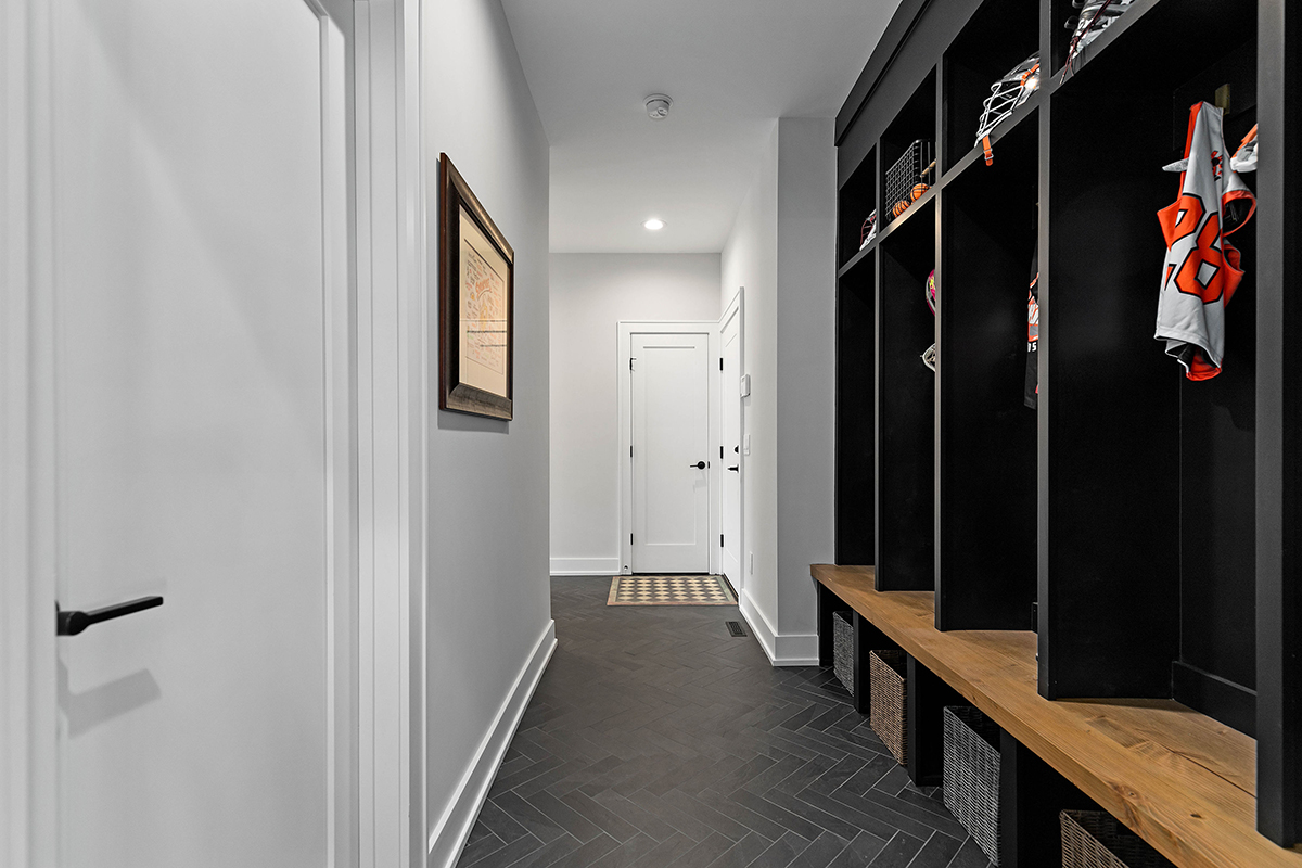 diagonal stone flooring in mudroom. closet space is made up of black and brown wood, with wicker baskets underneath.