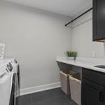 laundry room with black stone flooring, black cabinetry, and stone countertops.