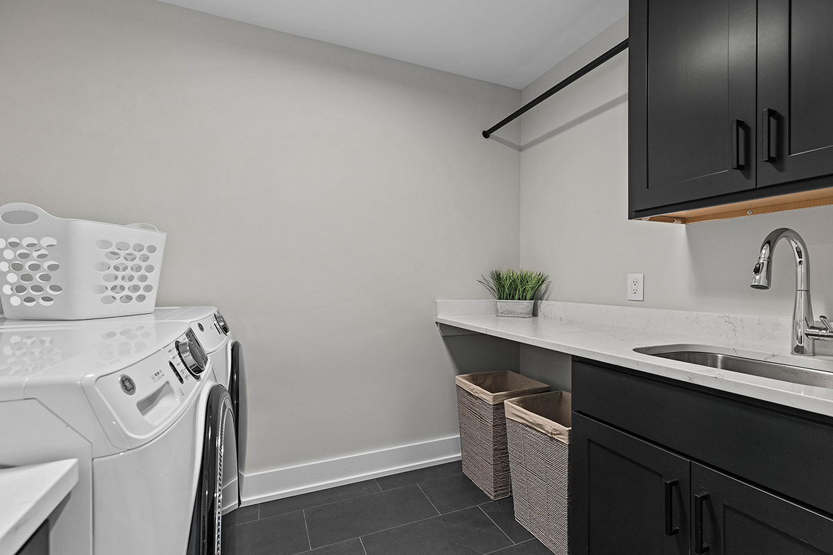 laundry room with black stone flooring, black cabinetry, and stone countertops.