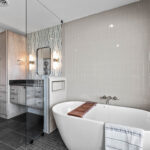 this angle of the bathroom shows the large tub along with the built in dual sinks, and the large linen cabinet.