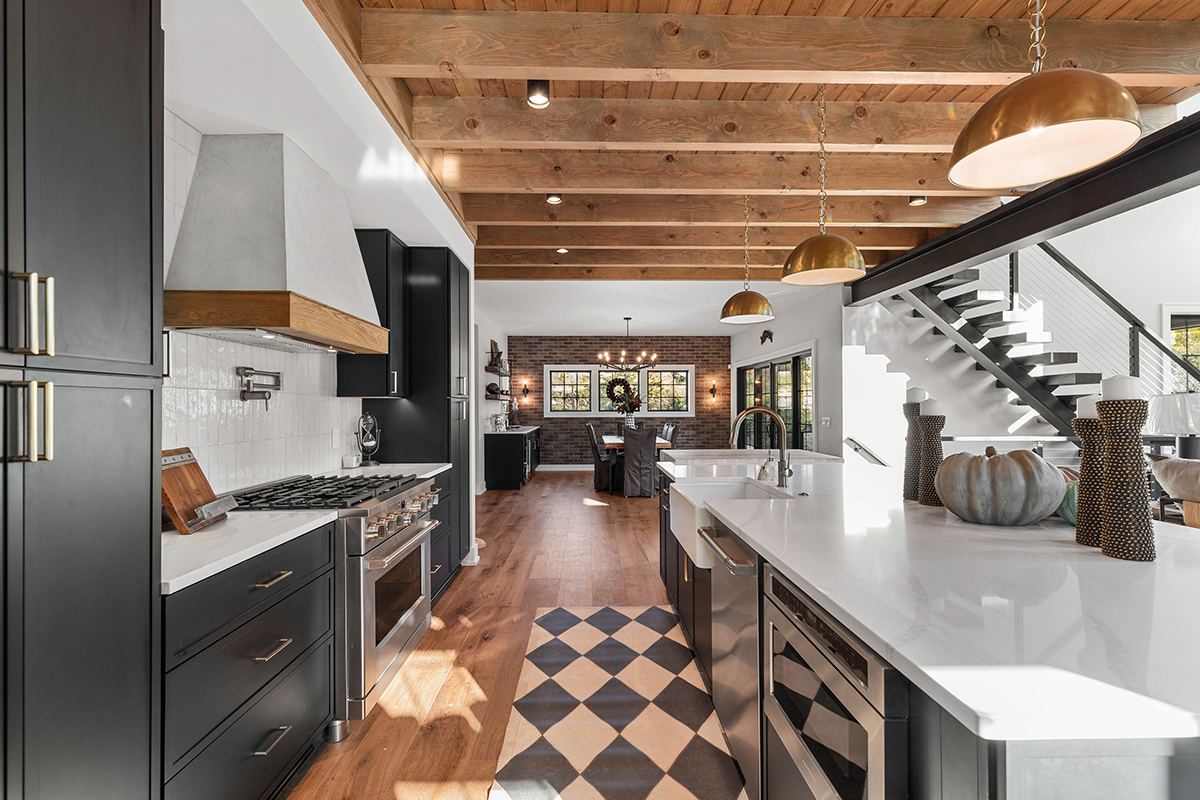 A kitchen with black cabinets and an exposed wooden beam ceiling.