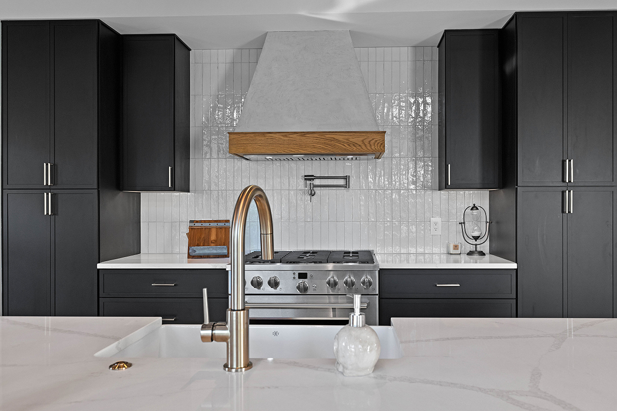 A black and white kitchen with a marble counter top. The walls are a white subway tile; the fixtures are a polished silver color.