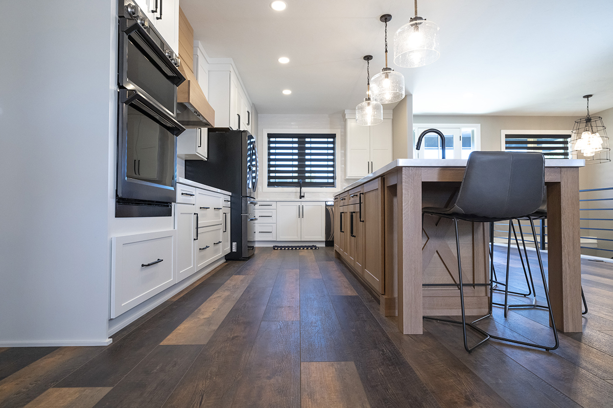 Shows dark vinyl flooring with white cabinets along the wall with a neutral brown island