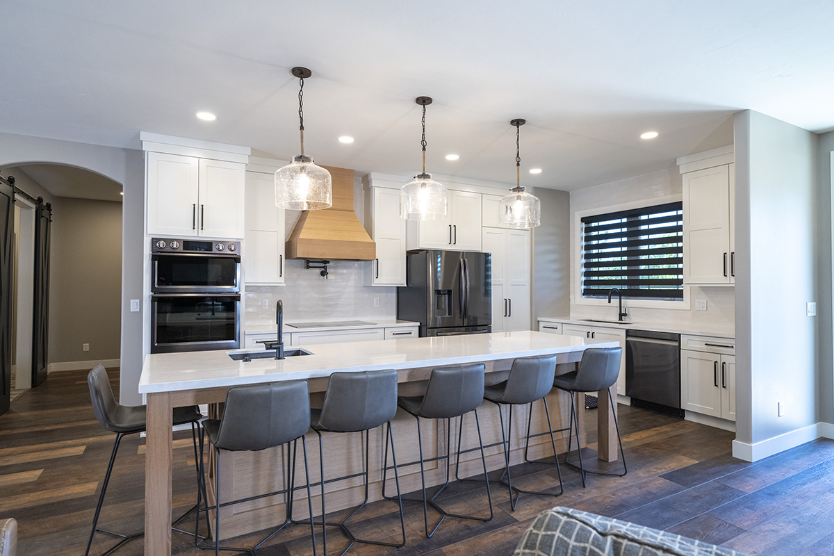 Shows island with chairs under it and wide frame of the kitchen