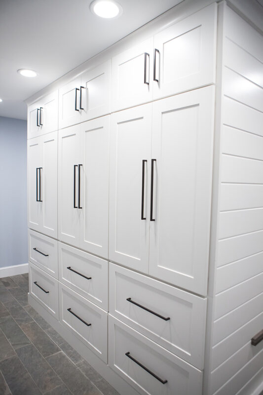 rear side of white mudroom cabinetry. Mudroom cabinets float in the middle of the room.