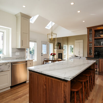 A kitchen with marble counter tops and wooden cabinets.