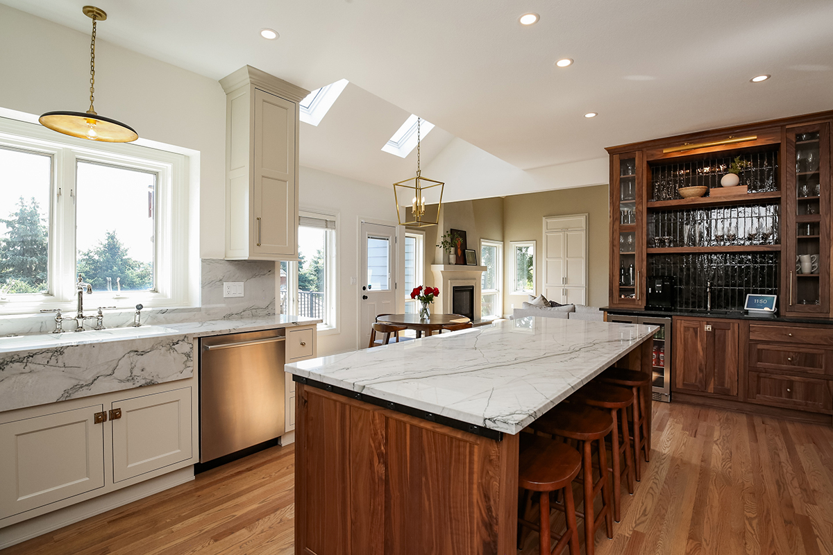 A kitchen with marble counter tops and wooden cabinets.