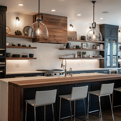 A kitchen with a large island and bar stools. The kitchen is white with black cabinets and wood accents.