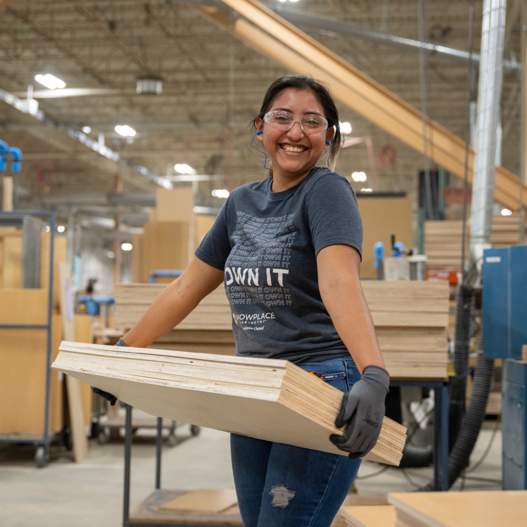Smiling employee carrying wood panels