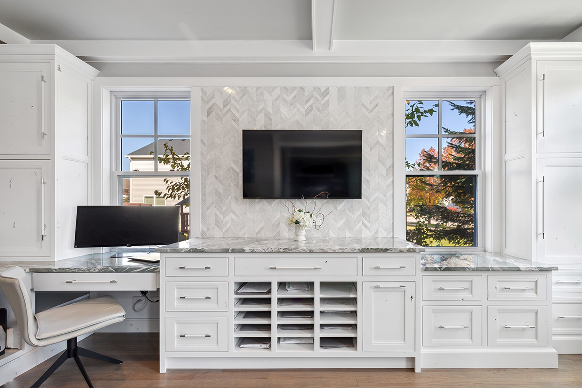 Built in cabinets and the drawers in the office with windows behind the computer monitor.