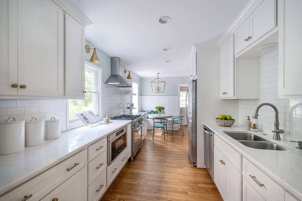 White hallway kitchen with white cabinets. The cabinets have silver hardware.