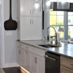 We see the dishwasher and the sink beside it. There is a under cabinet lighting that is featured in this photo.