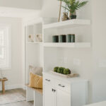 Built in benches, white cabinets, and floating shelves in the entry way of the house.
