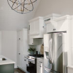 The main kitchen is shown with the all white cabinets and you can see the tongue and grove ceiling that is also white.