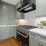 large stovetop in between light green cabins with white countertops
