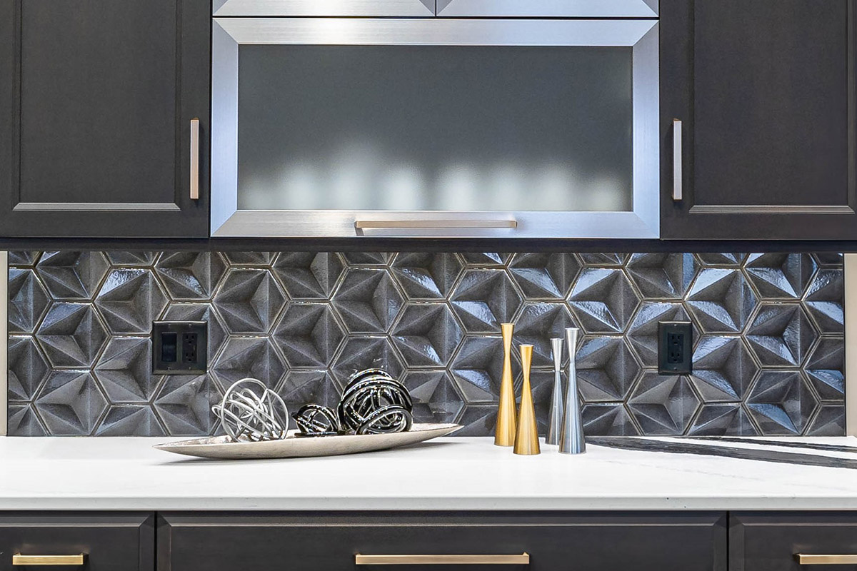 patterned hexagonal gray backsplash with white countertops and dark gray cabinets