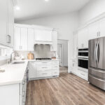 all white kitchen with silver hardware and white appliances and large gray stainless steel fridge