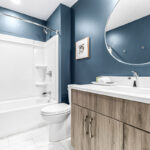Another bathroom with brushed, natural wood vanity. This bathroom is a deep blue color.