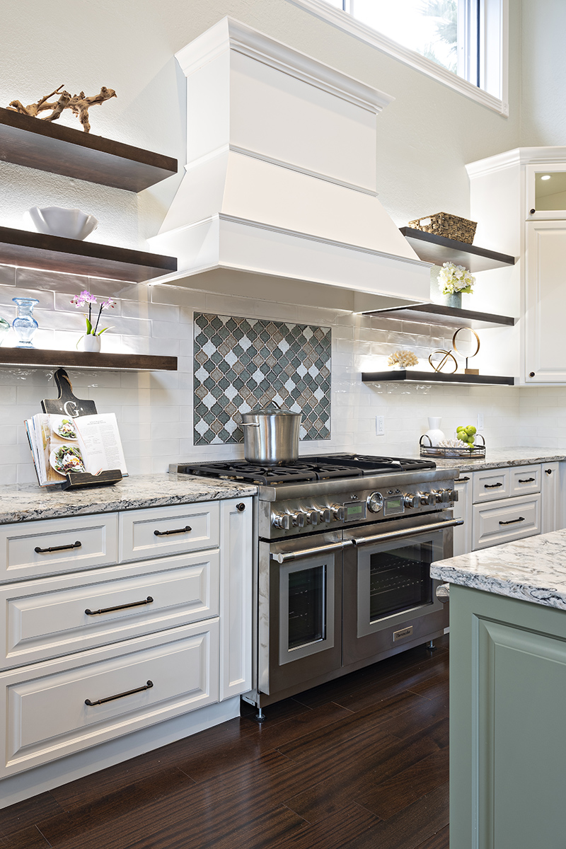 white kitchen cabinetry with black hardware, stainless steel stove with white hood range