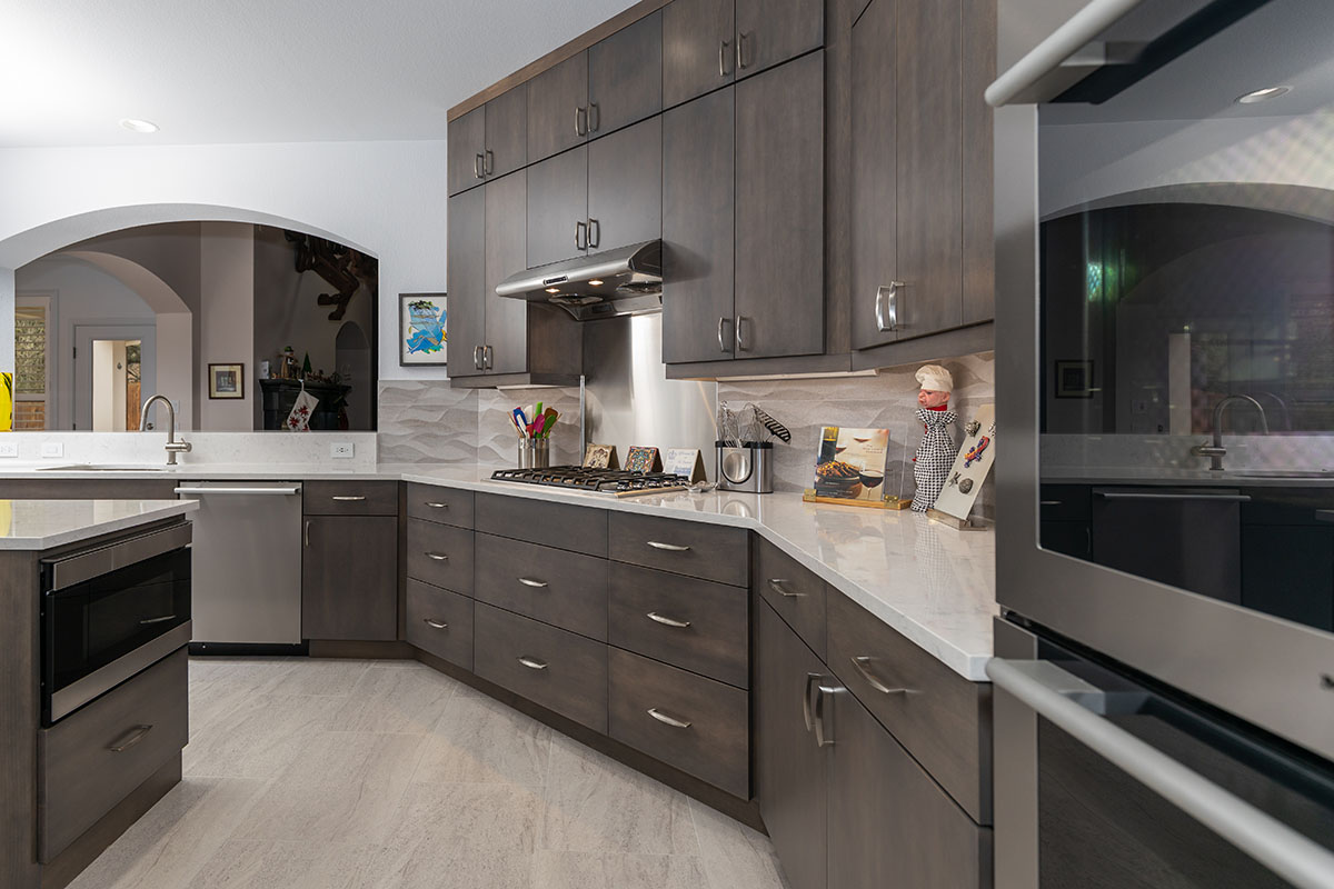 all brown cabinetry with white countertops and silver appliances