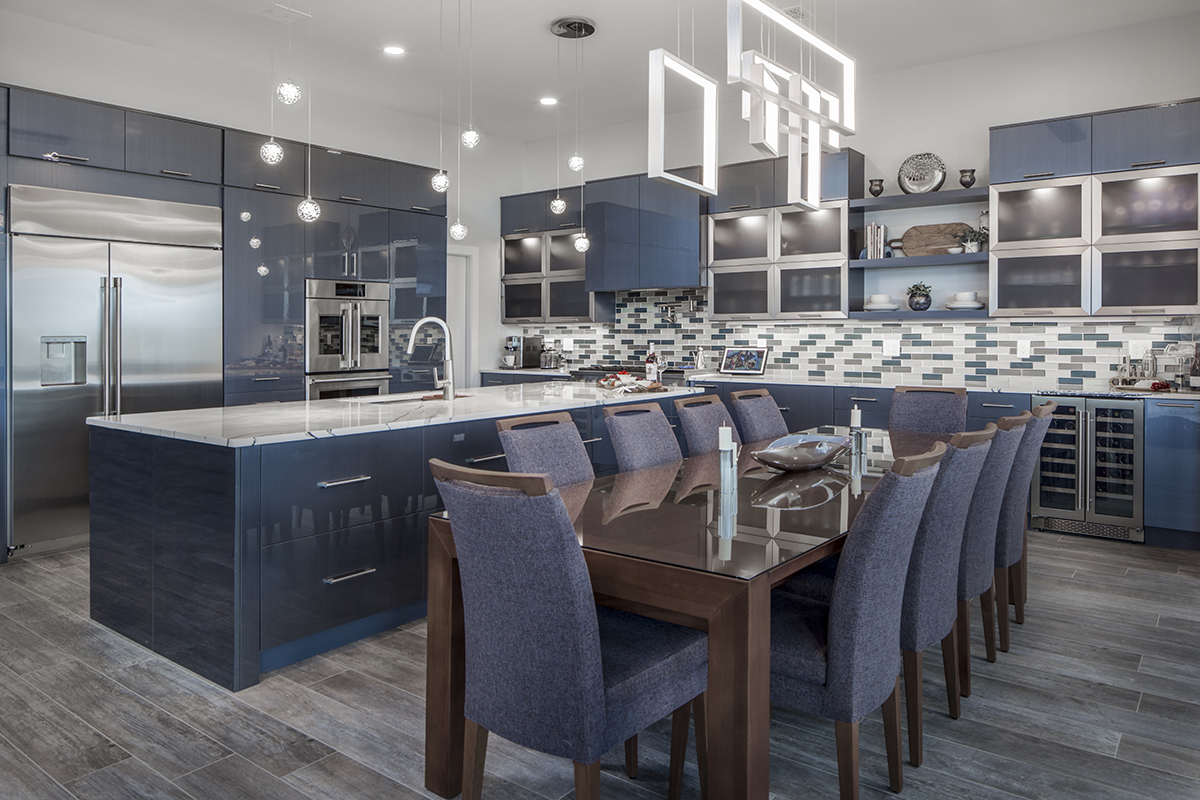 modern kitchen with acrylic gloss cabinetry. Blue tones throughout the kitchen aside from the multicolored tile backsplash and stainless steel appliances.