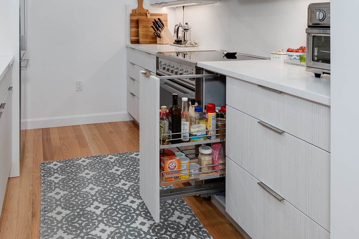Picture shows a hallway kitchen that features a pull out cabinet for cooking oils, condiments, and spices.