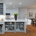 modern white kitchen cabinetry and bar setup with bright wooden flooring. floorplan opens to dining table.