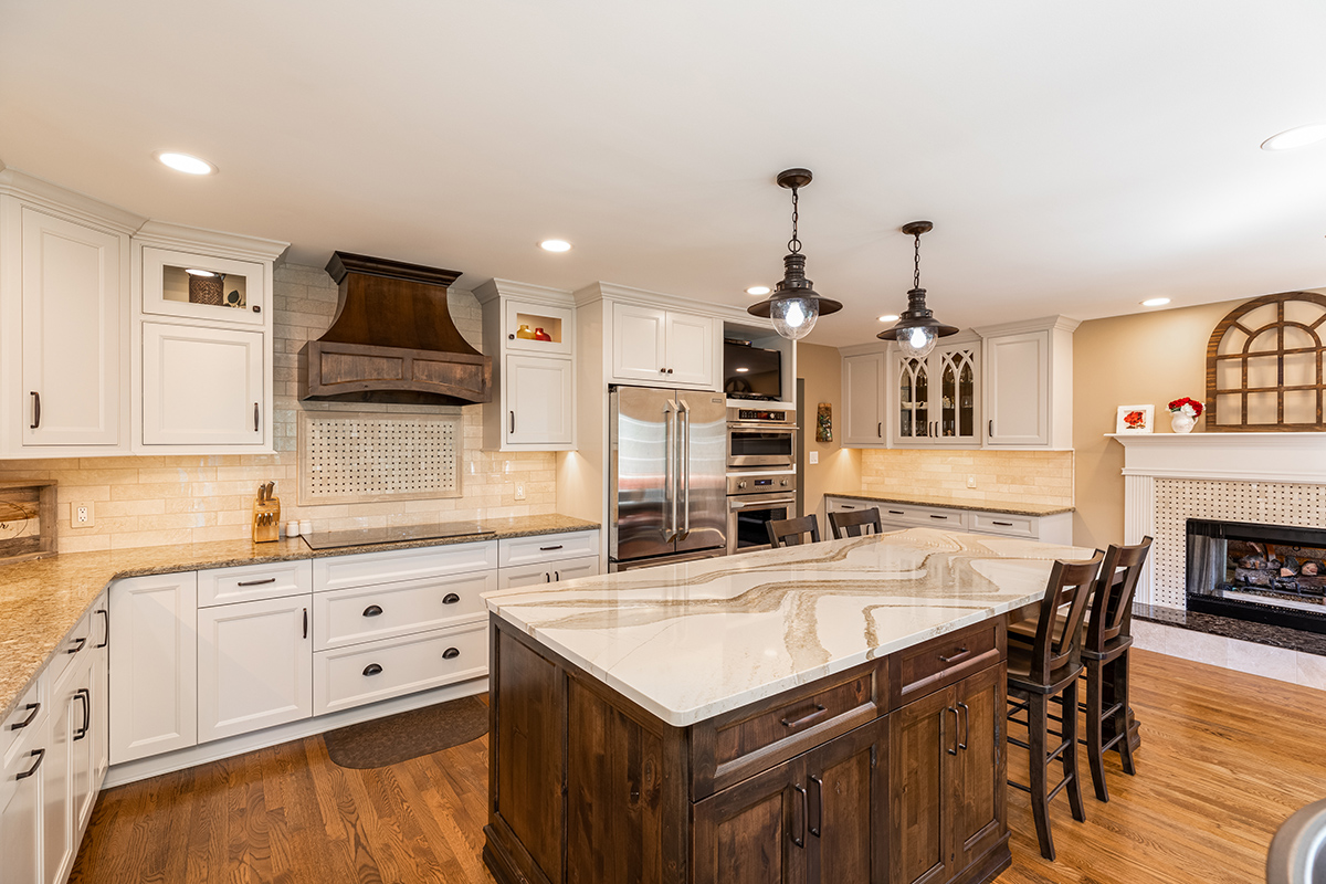 natural wood floors with white cabinets and dark wood cabinet island. The appliances are stainless steel. the handles of the cabinets in the kitchen are two different styles - one is a long skinny handle and the other is a half dome under cling that can be used to pull out the drawer.