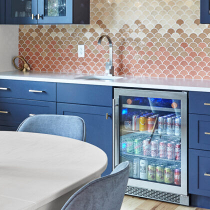 blue mini bar with stocked fridge and fish scale backsplash