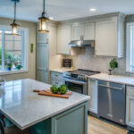 soft green kitchen island sits under stone countertops. White inset cabinetry throughout the rest of the kitchen. Stainless steel appliances.