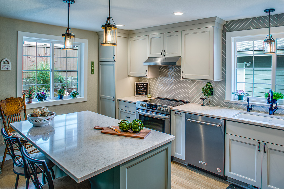 soft green kitchen island sits under stone countertops. White inset cabinetry throughout the rest of the kitchen. Stainless steel appliances.