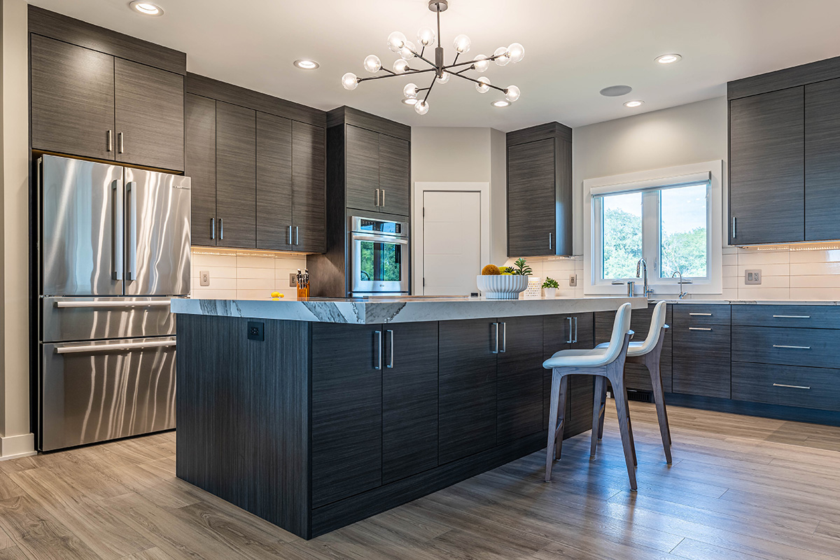 Brushed black wooden cabinetry in modern kitchen. Patterned stone countertops and stainless steel accessories.