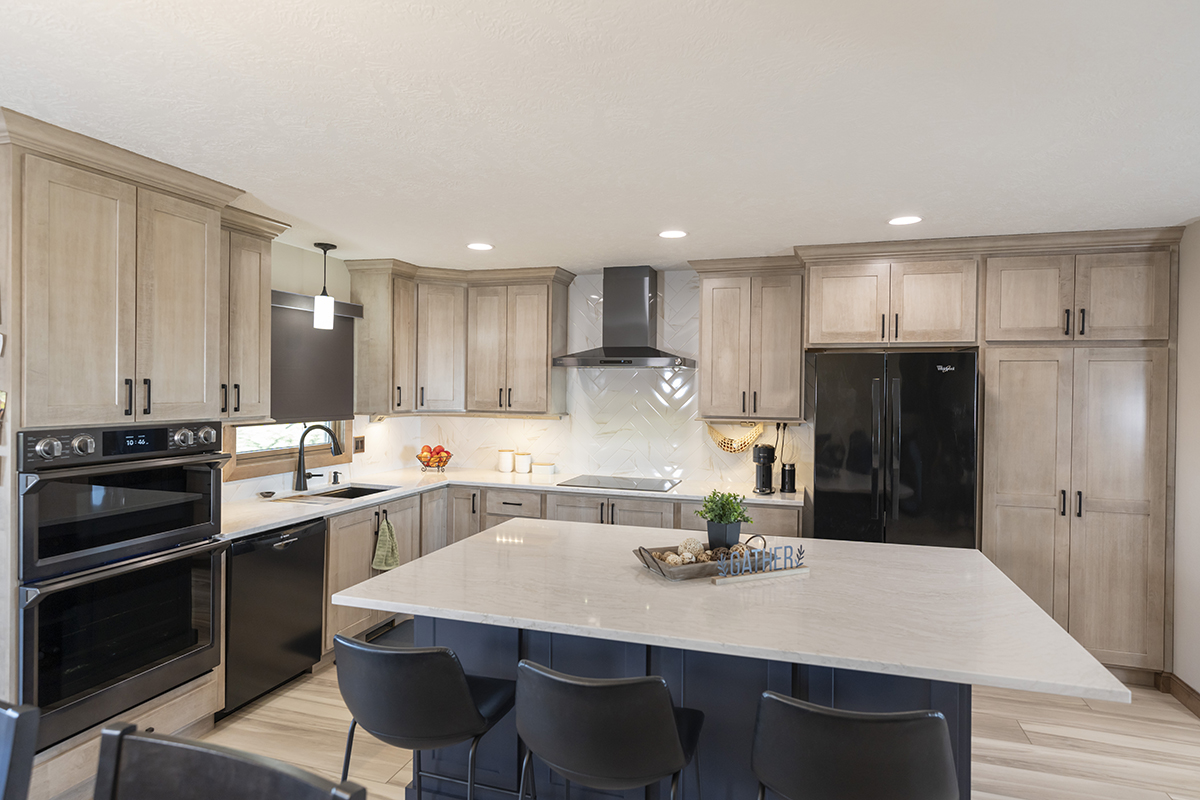 Clean kitchen with soft and smooth kitchen cabinets. The large white island countertop sits on top navy cabinetry.