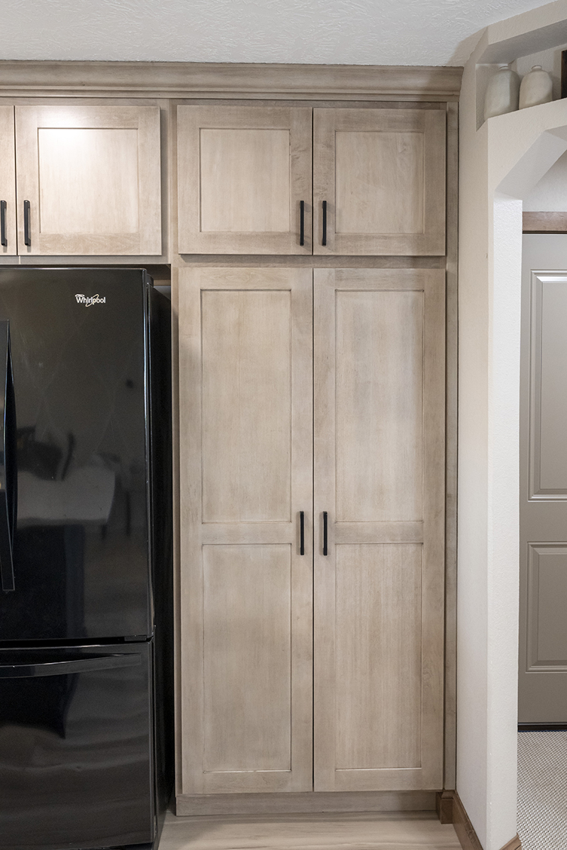 smooth wooden pantry doors with black finishes on the handles.