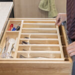 wooden silverware drawer protruding from white stone countertop.