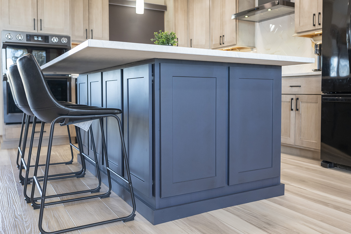 gray island cabinetry with white stone island countertop. Two leather chairs are tucked under the island.