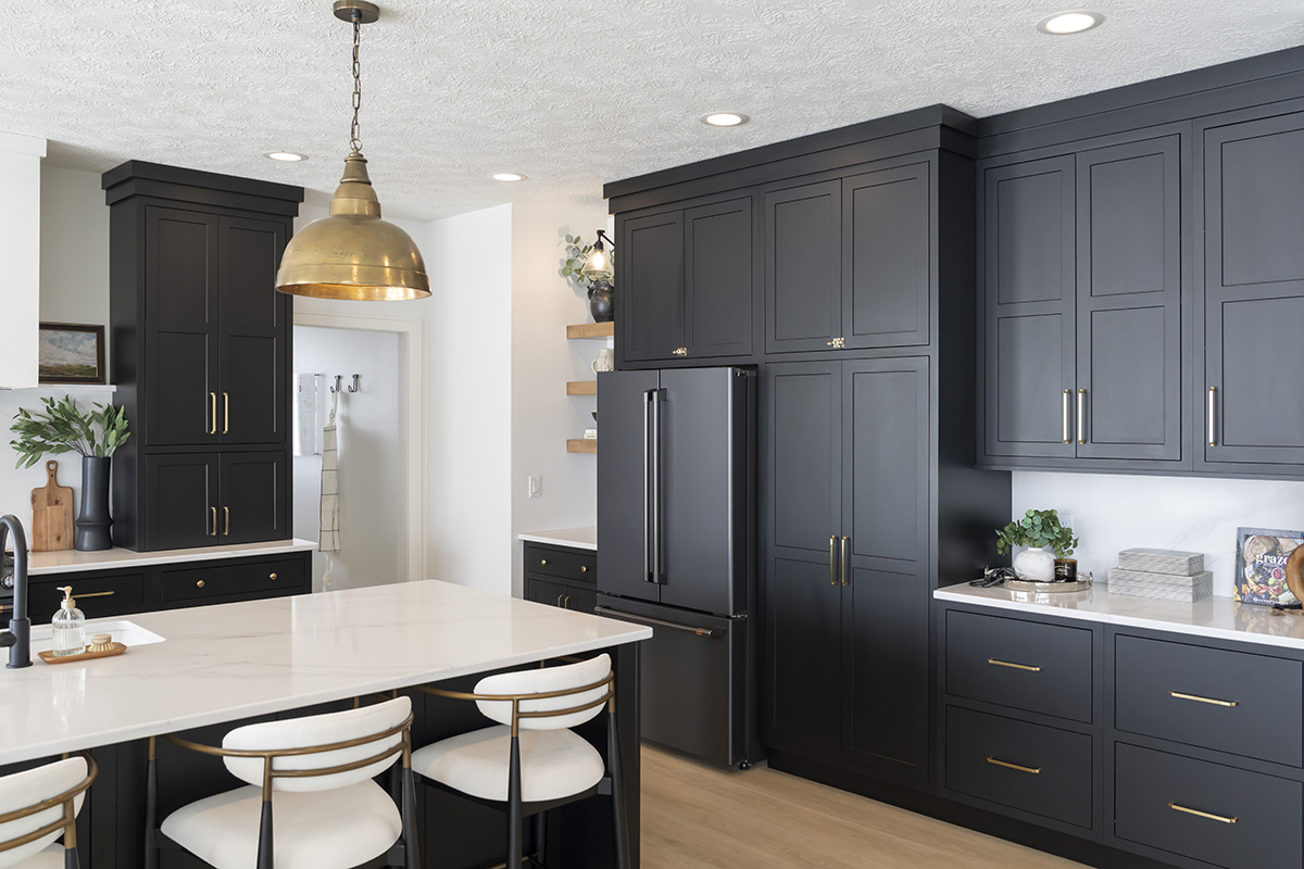 dark black kitchen cabinetry with dark gray appliances. White stone countertops including the stone island with white stools.