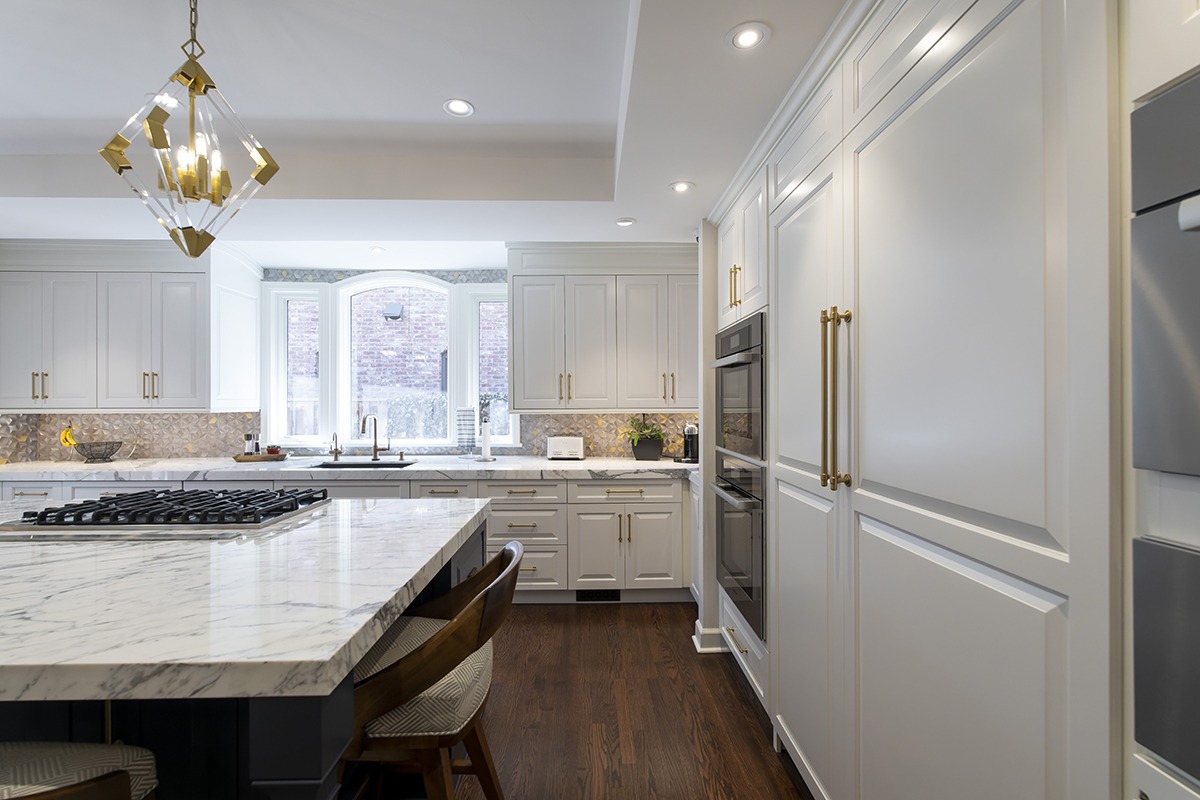 all white kitchen with gold accents and dark hard wood floors.