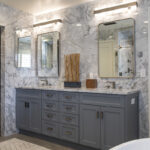 gray wooden bathroom vanity with marbled stone countertops. Stone marbled walls.
