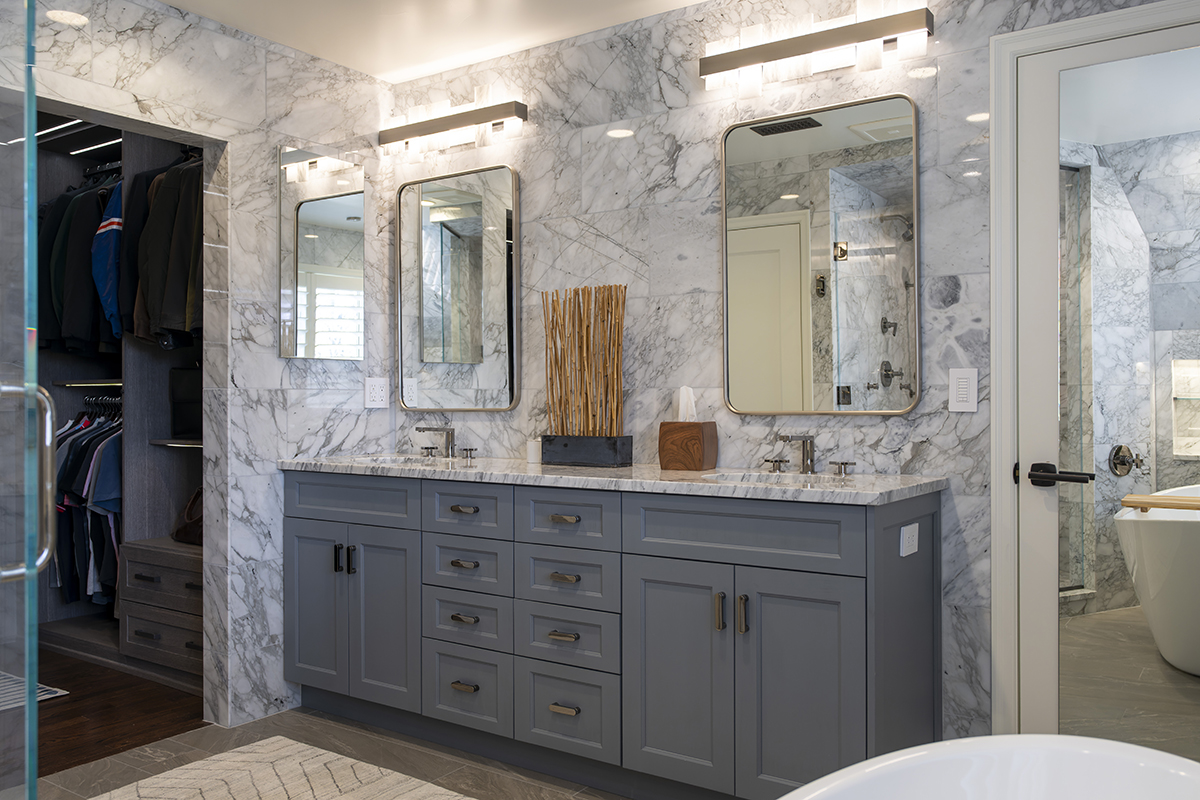 gray wooden bathroom vanity with marbled stone countertops. Stone marbled walls.