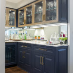home bar with black cabinetry and gold accents, holding glassware for drinks.