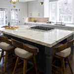 white kitchen cabinets with a large stone island dining setup