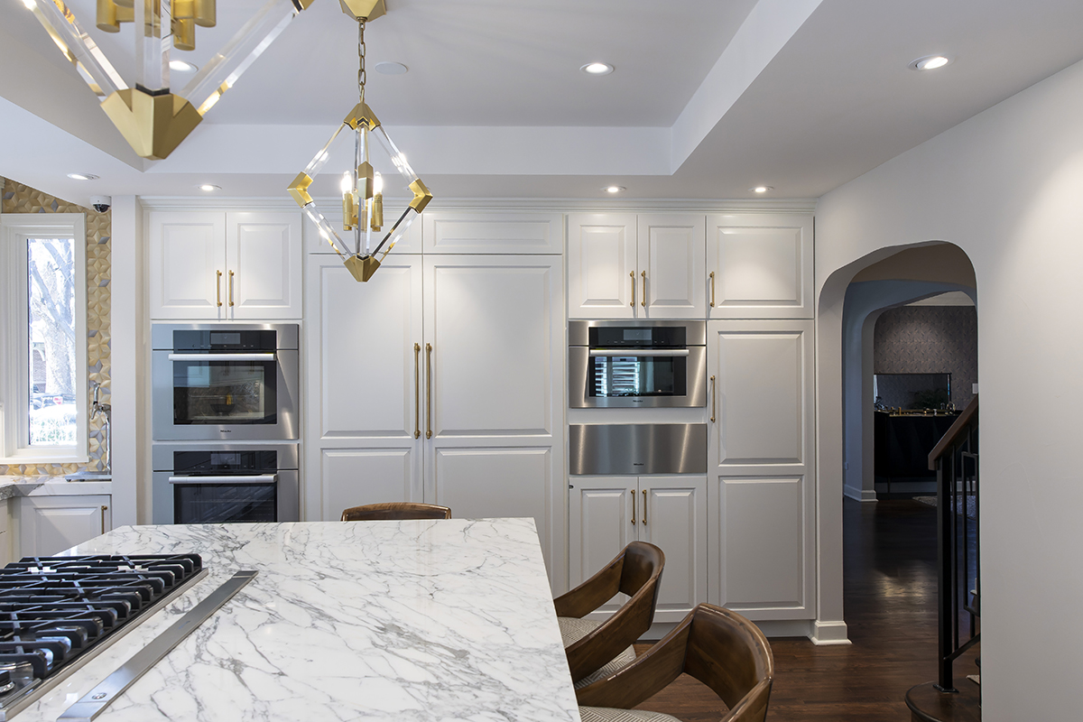 modern white kitchen with stone countertops, and brass accessories.