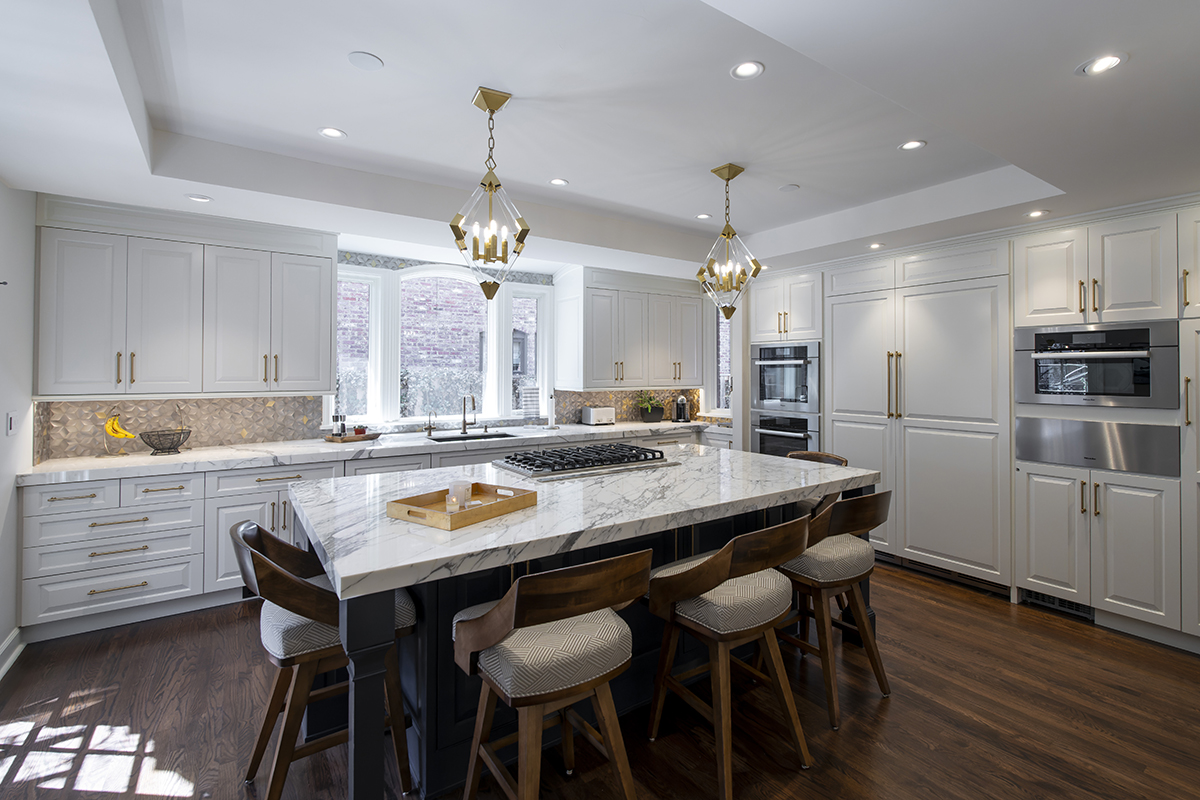 white cabinet kitchen with gold accents and warm wooden floors and chairs